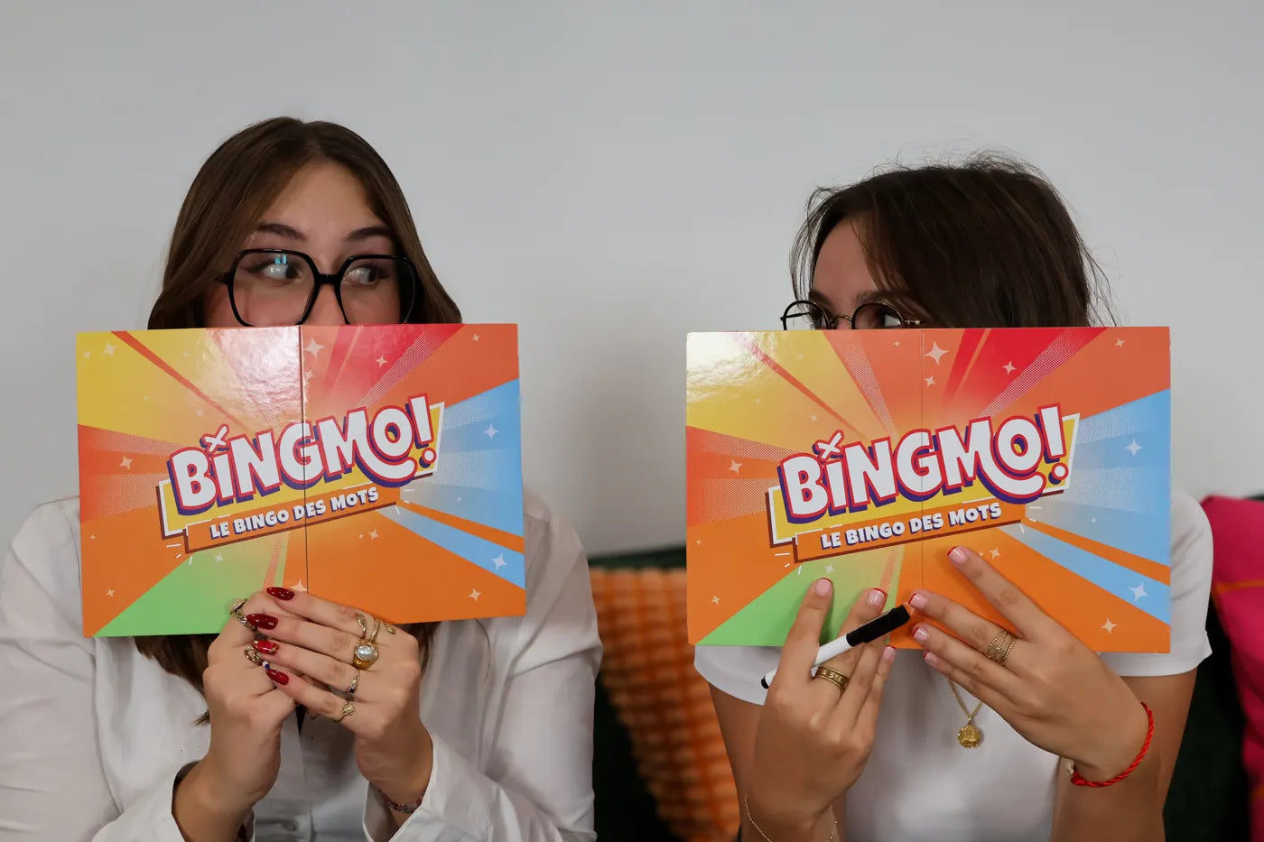 Two friends hide their faces behind a Bingmo grid